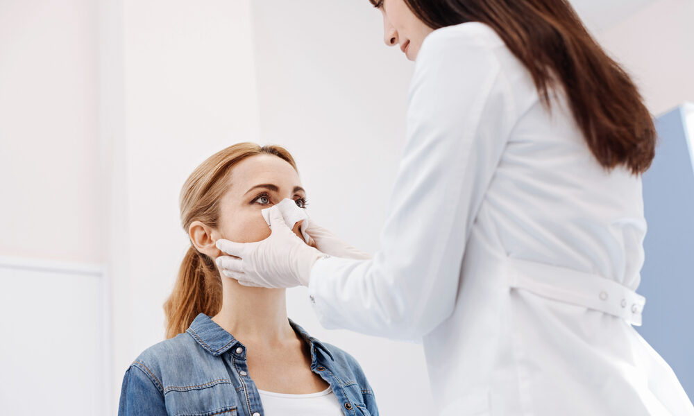 Médica coloca curativo em paciente depois de realizar a rinoplastia ultrassônica